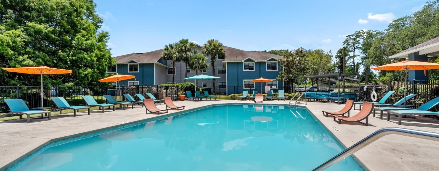 a swimming pool with lounge chairs and umbrellas